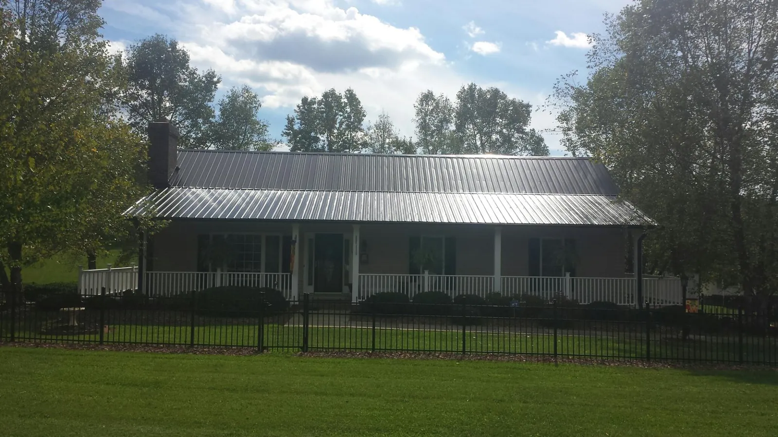 Gray metal roof on a brick ranch with a full width front porch — Gutter Guard Installation work by our crew in New Richmond