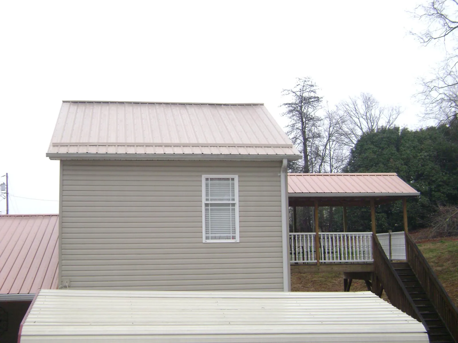 Tan metal roofs on a two story addition and attached porch, from a Roof Replacement job in New Richmond