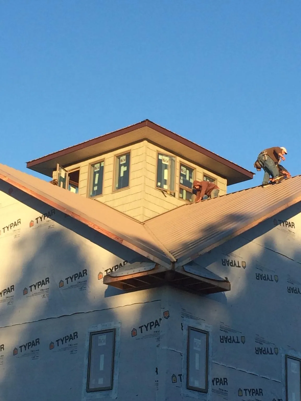 Roofers working around a rooftop cupola on a new metal roof at sunset — Roof Waterproofing in New Richmond by Roofing Brothers